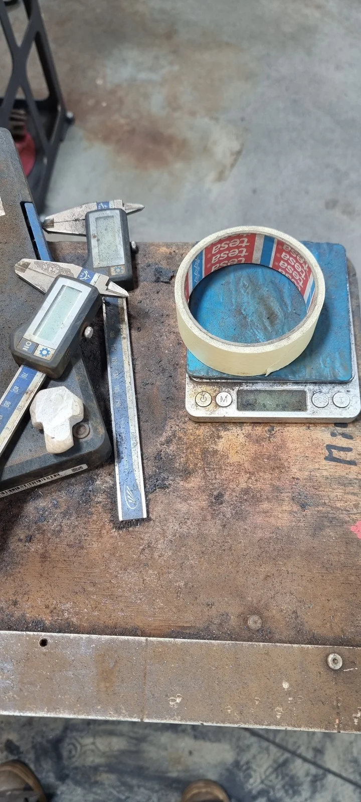 Measuring tools on a workbench; at the lower left is an unfinished Thor’s hammer made from a found stone.